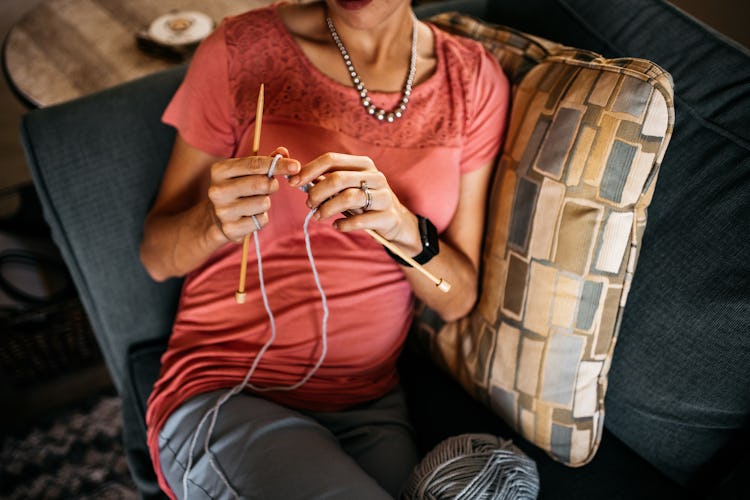 Pregnant woman with an eating disorder sitting in a sofa knitting