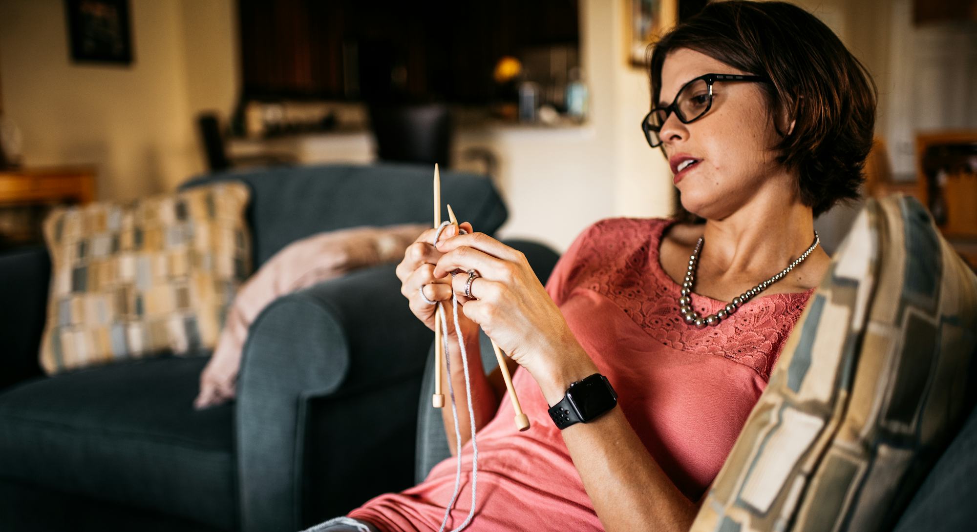 Pregnant woman with an eating disorder wearing glasses and a pearl necklace while checking her phone