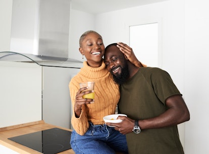 Couple cuddles in their kitchen after baby talking.