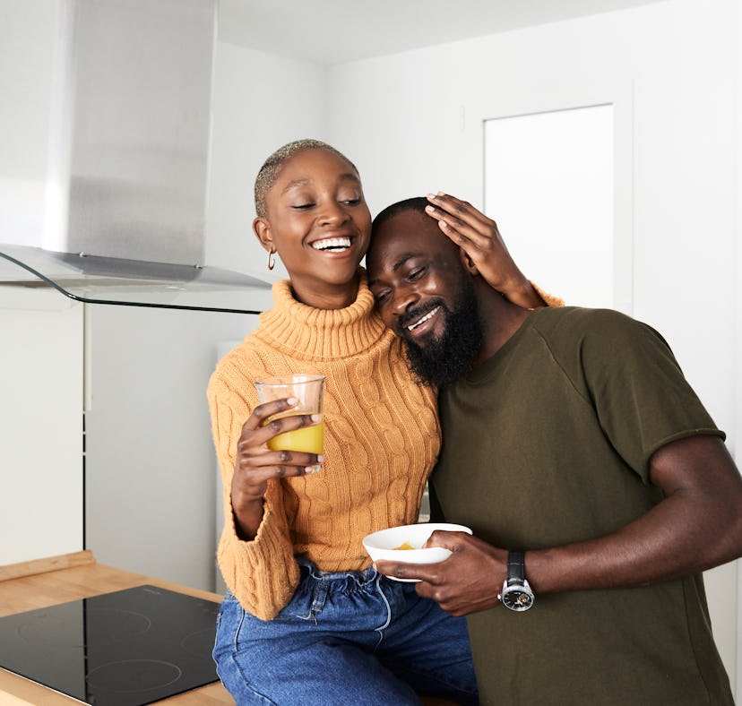 Couple cuddles in their kitchen after baby talking.