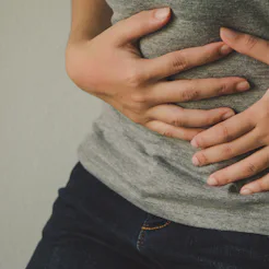 A person holding their stomach as they experience Adenomyosis
