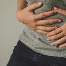 A person holding their stomach as they experience Adenomyosis 