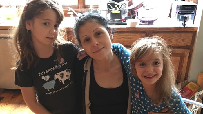 A mom who got a tattoo, posing for a photo with her two daughters