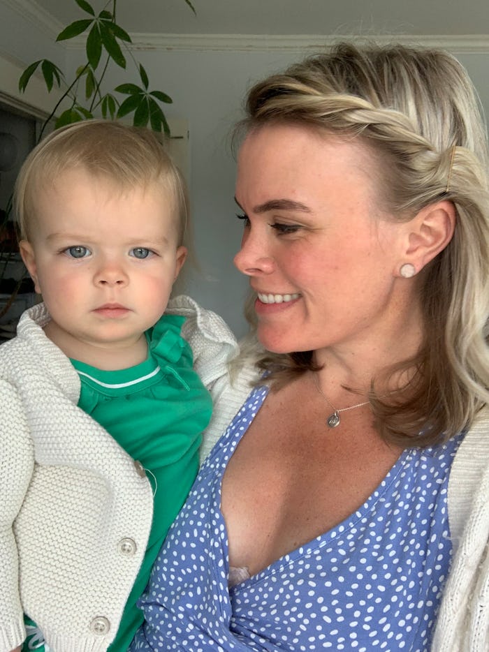 Beth Loster wearing a polkadot blue dress while holding her baby in her arms