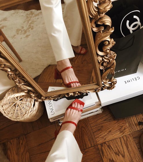 A woman taking a photo of her left leg while wearing a red naked sandal