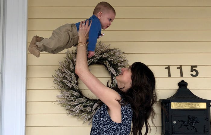 A mom playing with her 6-month-old by lifting him up in the air