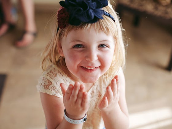 A child smiling in a photo made by a wedding photographer, who knows how to get the kids to pay atte...