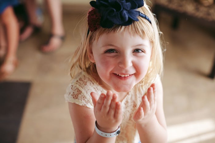 A child smiling in a photo made by a wedding photographer, who knows how to get the kids to pay atte...