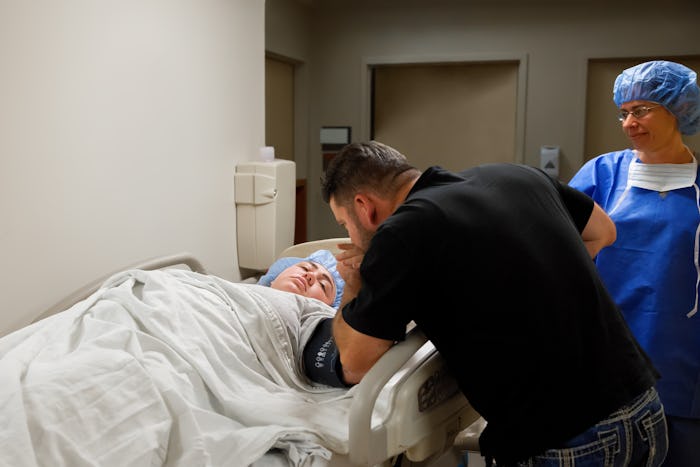 A man comforting a woman who is lying in a hospital bed before her C-section