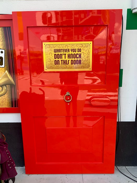 A red door with "whatever you do don't knock on this door" text sign