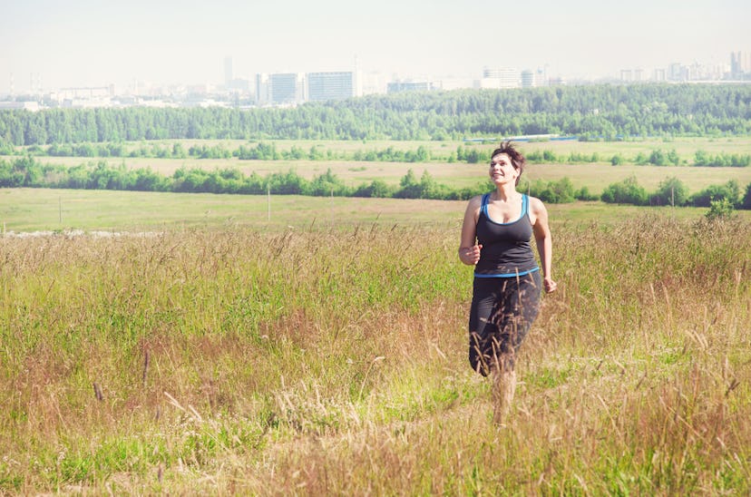 A woman happily jogging in the nature far from the city