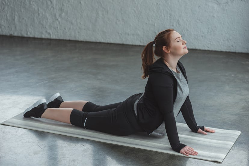 A woman in sportswear stretching on a yoga mat.