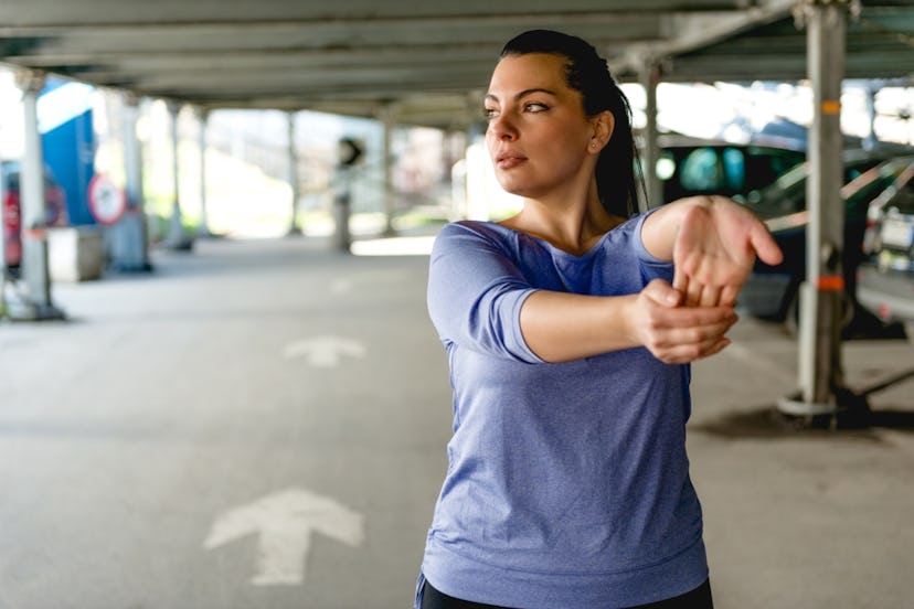 A woman stretching in the parking lot.