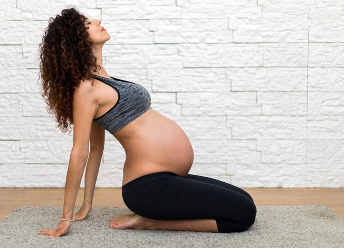 A pregnant woman doing yoga on a yoga mat, in workout clothes