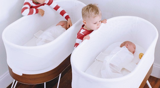 Two babies sleeping peacefully in SNOO Smart Sleeper bassinets, as their older siblings check on the...