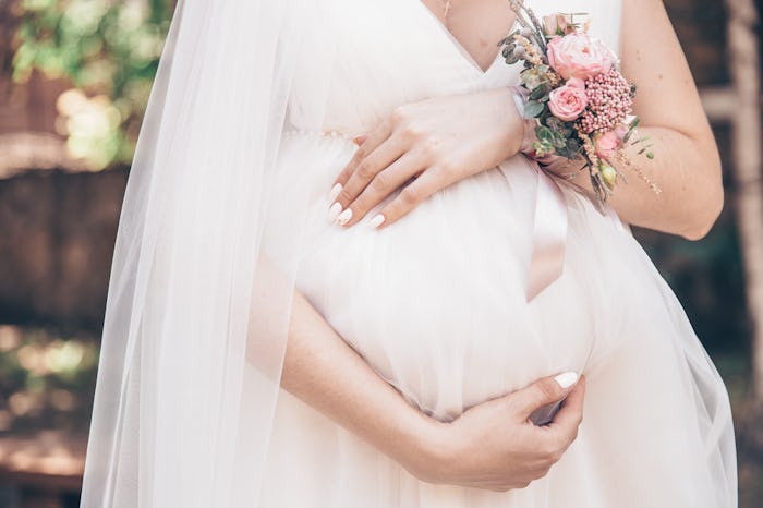 A woman in a maternity wedding dress