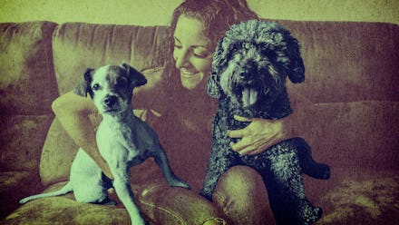 A woman sitting on a couch holding her two pet dogs on her lap