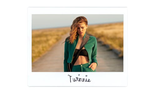 Singer Twinnie Moore wears a green two-piece suit and a black top and stands in the middle of the st...