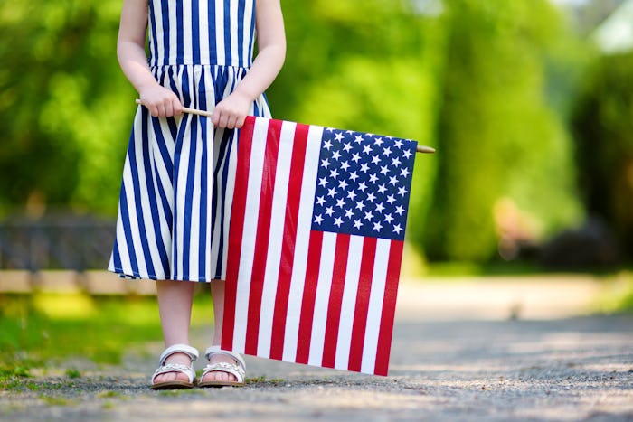 a little girl standing with an american flag