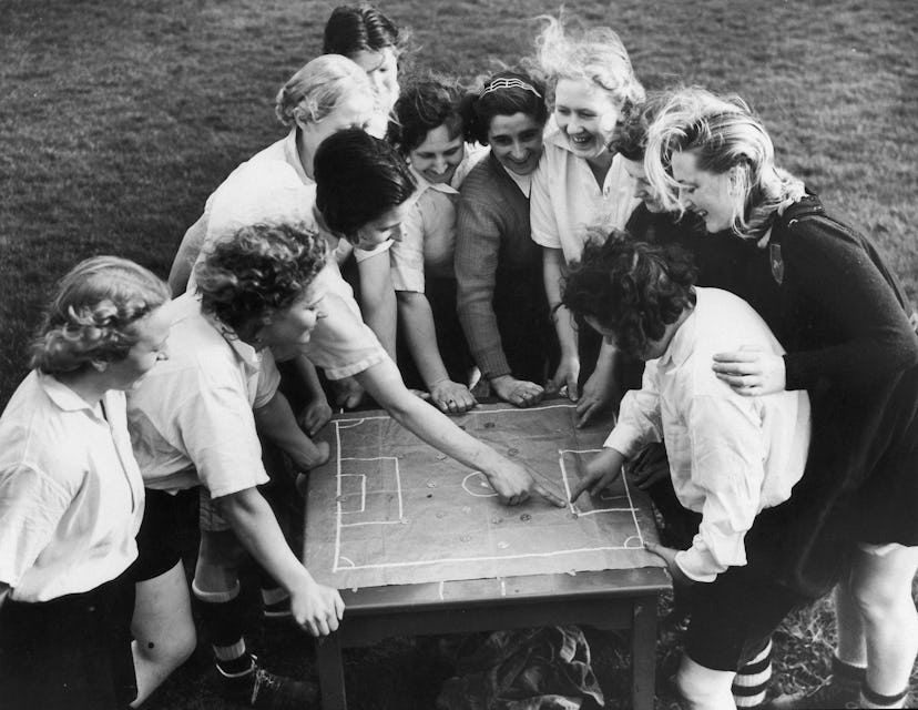 A black and white vintage photo of Lily Parr revising a strategy with her teammates.