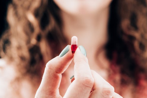 A woman holds up a vitamin supplement. Experts explain misconceptions about supplements.