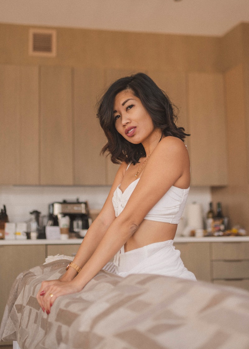 Lisa Linh posing in a white top next to a couch on a kitchen
