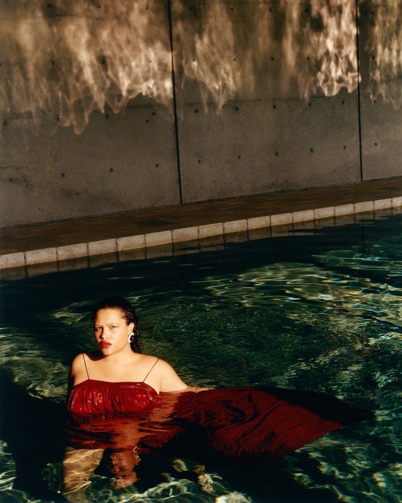 Alva wearing a red dress while in a swimming pool
