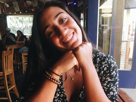  Isabel Thottam, a biracial Indian American, smiling for a photo in a coffee shop