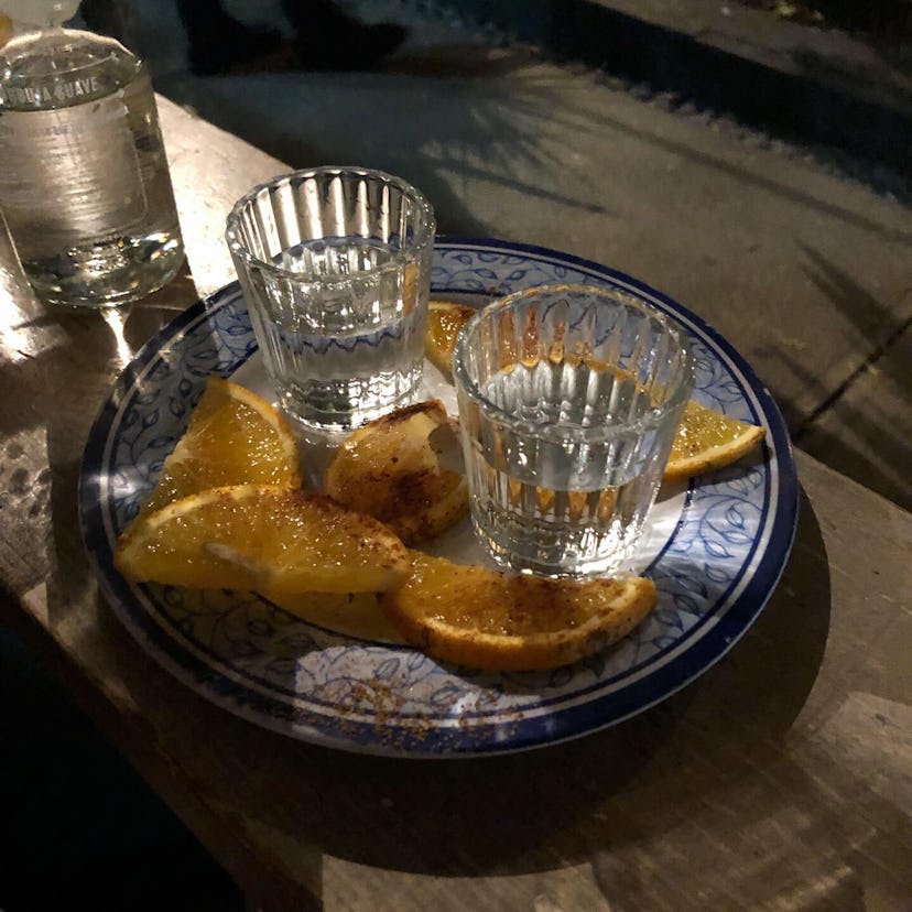 Two glasses of tequila without ice and slices of lemon on a plate