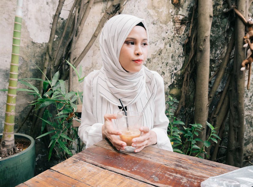 Young woman having cold coffee at a cafe before posting on Instagram with an iced coffee caption.