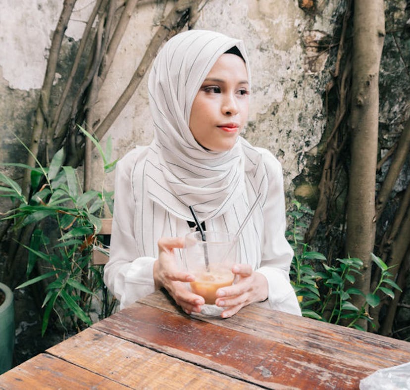Young woman having cold coffee at a cafe before posting on Instagram with an iced coffee caption.