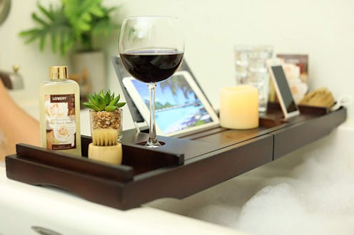 A dark wooden tray with a laptop, glass of wine and candles on it as a Mother's Day gift