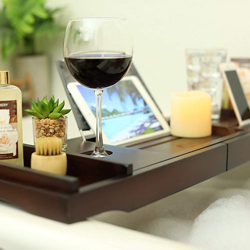 A dark wooden tray with a laptop, glass of wine and candles on it as a Mother's Day gift