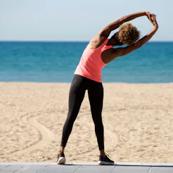 A Lyme disease survivor on a beach stretching out.