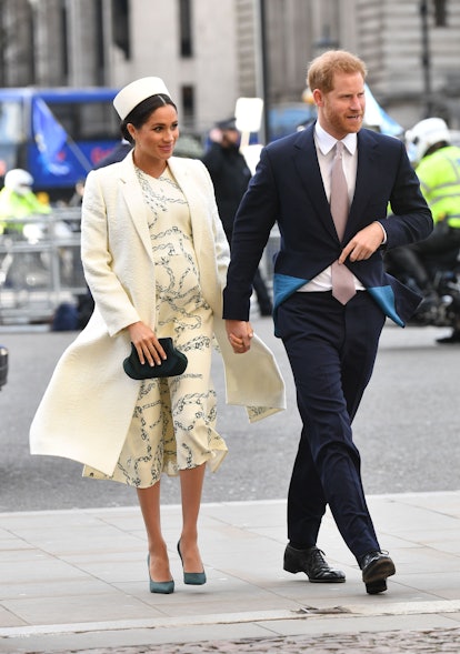Pregnant Meghan Markle and Prince Harry walking down a street
