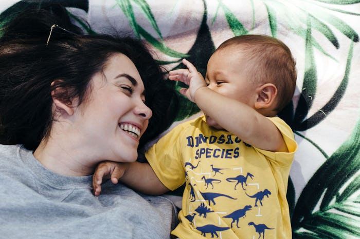 a mom and baby lying next to each other smiling