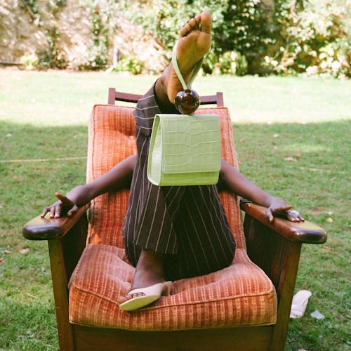 A model lying in a chair outside, while having a influencer approved bag dangling from her foot