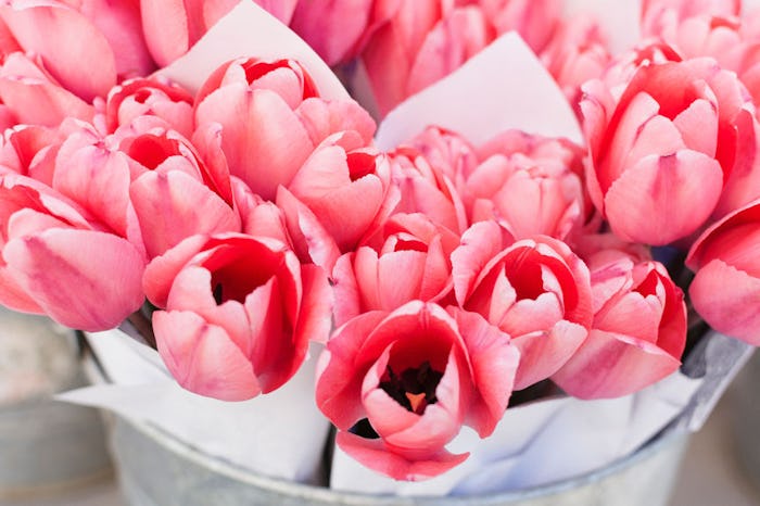 Bouquets of pink tulips stacked up in a metal bucket for sale at Whole Foods