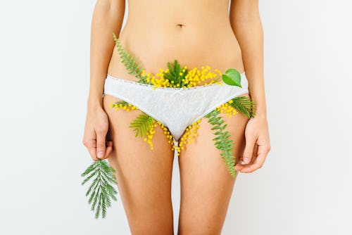 A woman in a pair of white underwear with flowers sticking out of it representing infertility and fe...