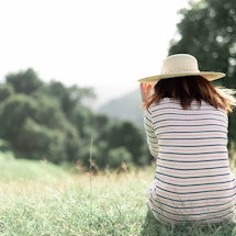 A woman sitting back turned to the camera on the grass in nature 