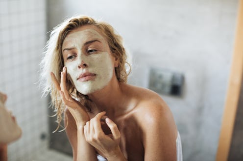 A young blonde lady putting an affordable skincare cream on her face