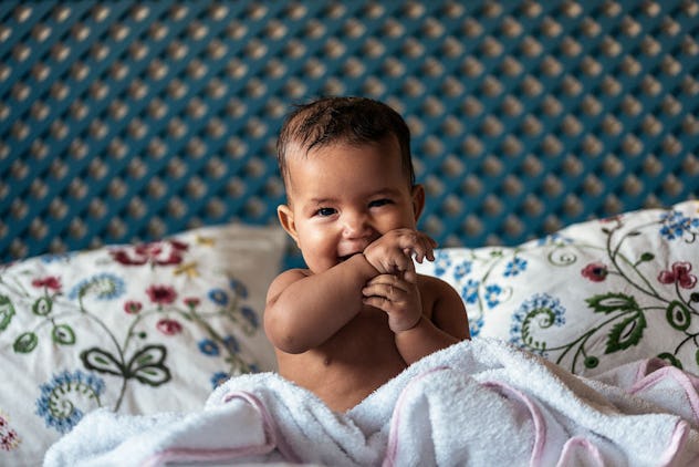 happy baby sitting up in bed 