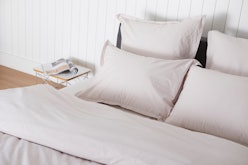 A bed with grey Parachute bedding on the duvet and four pillows