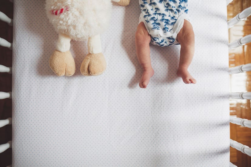 A baby and a stuffed toy in a bed