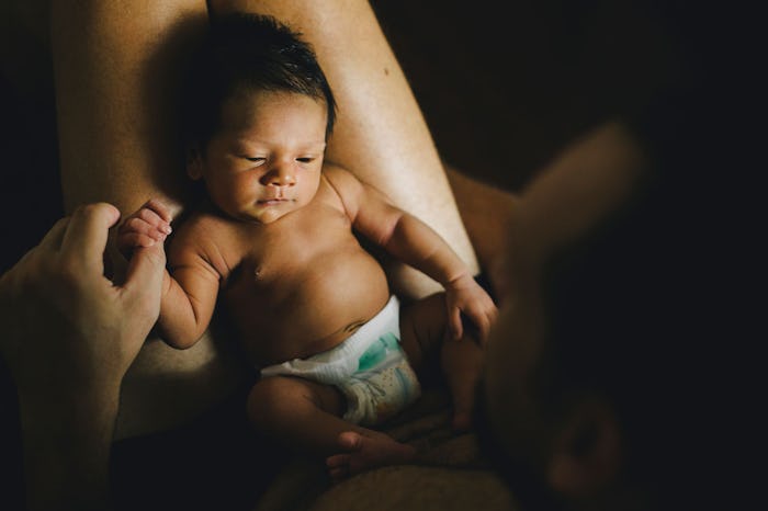 A mother holding the hand of her newborn baby