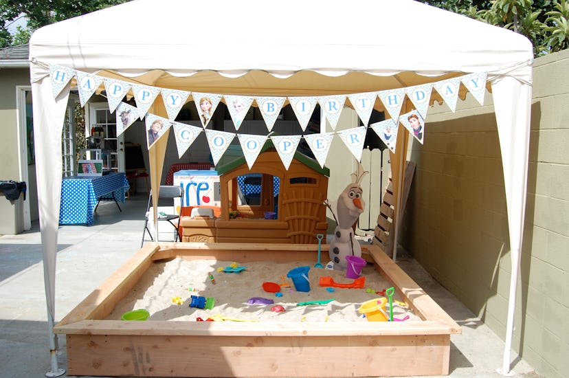 A sandbox playground with a beige tent during a birthday week