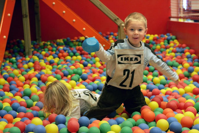 Two kids playing in the ball pit in IKEA's child play area wearing "IKEA" bibs