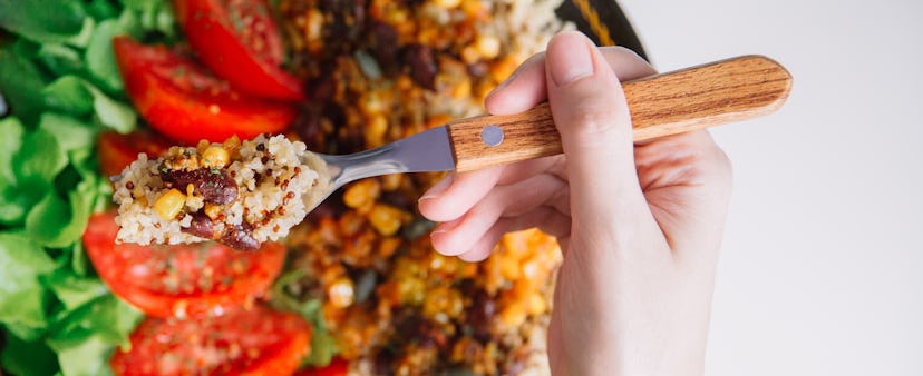 A woman eats a salad with quinoa and corn. Fiber rich foods can help your body's gut microbiome, whi...