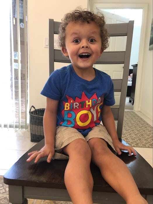 A little boy in a blue "Birthday Boy" t-shirt with an amused facial expression