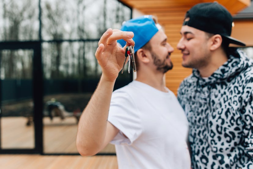 A man hugging with his friend and holding the keys of the house he bought